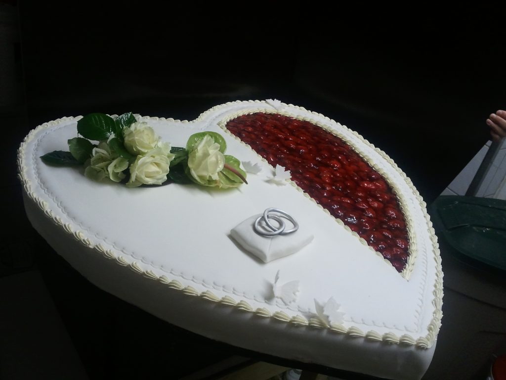 Hochzeitstorte in Herzform mit Erdbeerfüllung, weißen Rosen und Eheringen von Konditorei & Café Krüsmann Leipzig