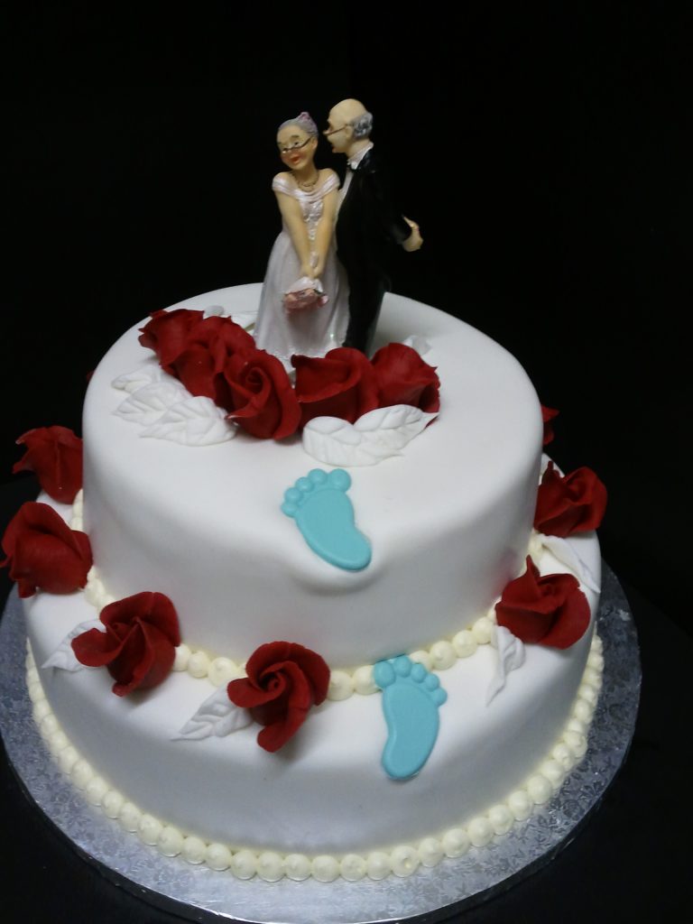 Humorvolle Hochzeitstorte mit Brautpaarfigur und roten Rosen – Konditorei & Café Krüsmann Leipzig